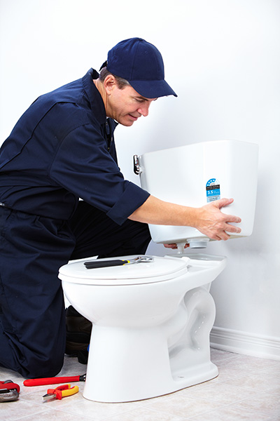 Plumber installing cistern with water rating label.