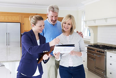 Image of a happy couple and a real estate agent standing in a kitchen discussing the WELS products in the property inclusions list.