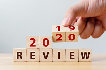 Image of 6 small wooden blocks are siting sided by side on a wooden table with individual letters on each, spelling out the word “Review” in the colour black. 4 same size wooden blocks are sitting on these blocks with numbers 2, 0, 2 and 0 respectively in the colour red, depicting the year 2020.