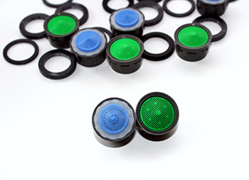 Image of two tap flow controllers in the foreground with black coloured outer surrounds with lime green and blue centres respectively. Also, a scattering of six of the same two-coloured tap flow controllers are in the background accompanied by black coloured fitment washers.